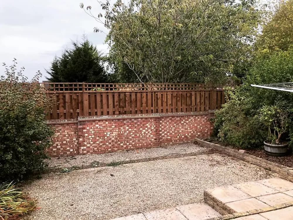 Hit and miss fencing with a trellis top, set on a low brick garden wall