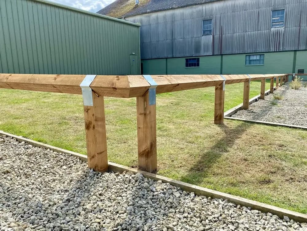Close view of knee-rail fencing with galvanised straps at the post joints