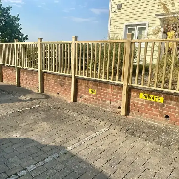 Timber spindle railing set on a low brick wall beside a driveway