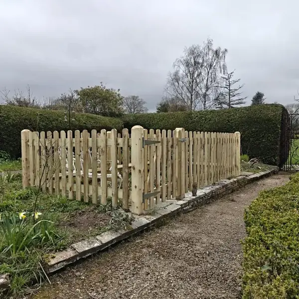 Round-top timber picket fence with a matching picket gate along a brick-edged garden path