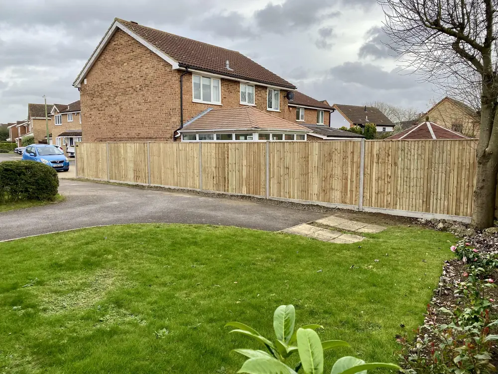 Closeboard fence running along a front garden beside a driveway on a residential street