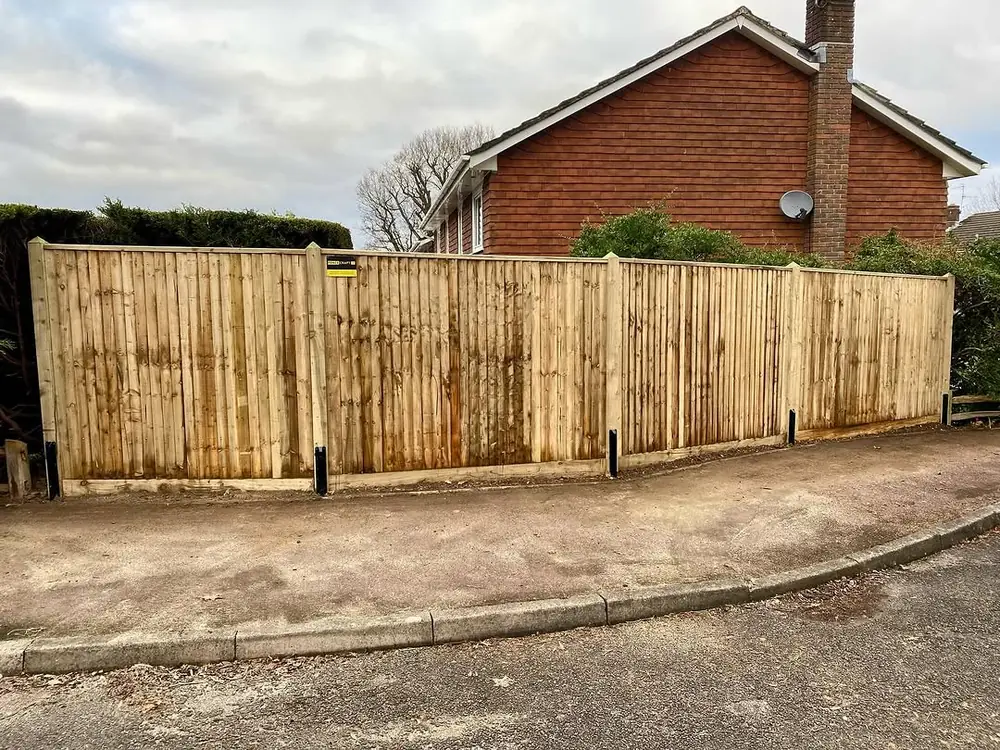 Curved run of closeboard fencing following a driveway around a detached brick house