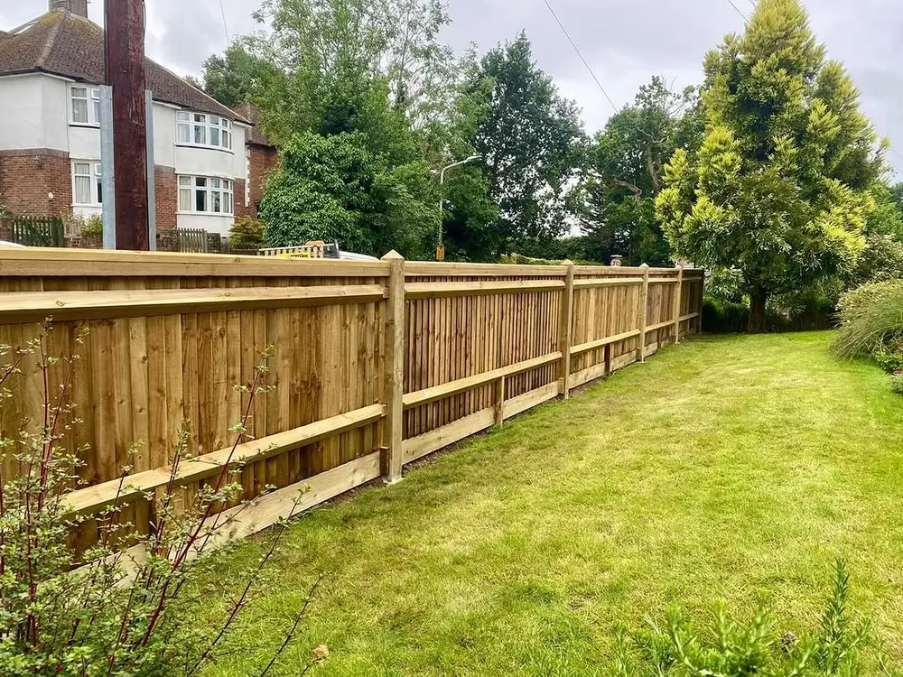 Closeboard fence with a post-and-rail return dividing two lawned gardens