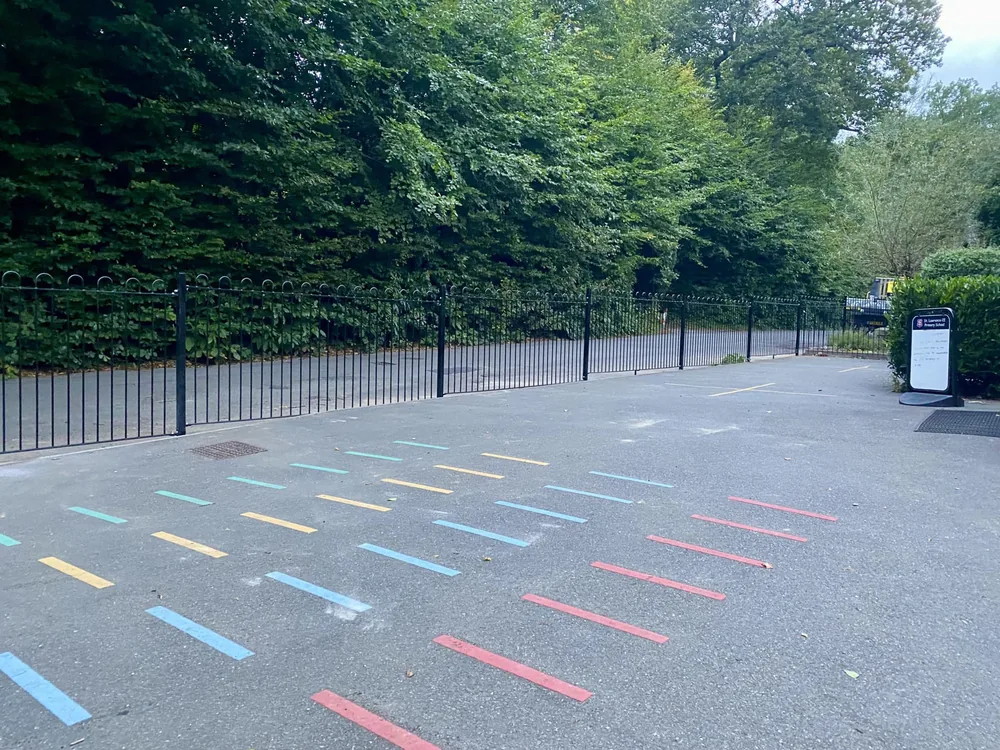 Bow-top railings enclosing a school playground with painted markings