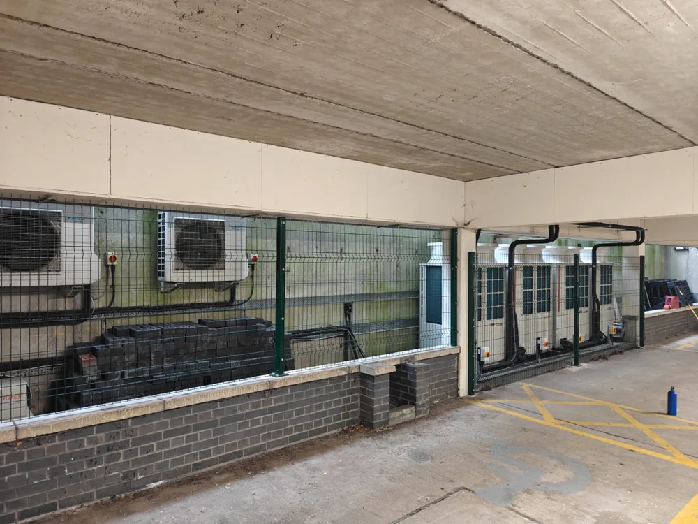 Mesh security fencing protecting air-conditioning units against a brick plinth