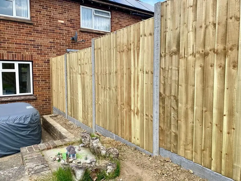 Closeboard panels between concrete posts along the side of a house