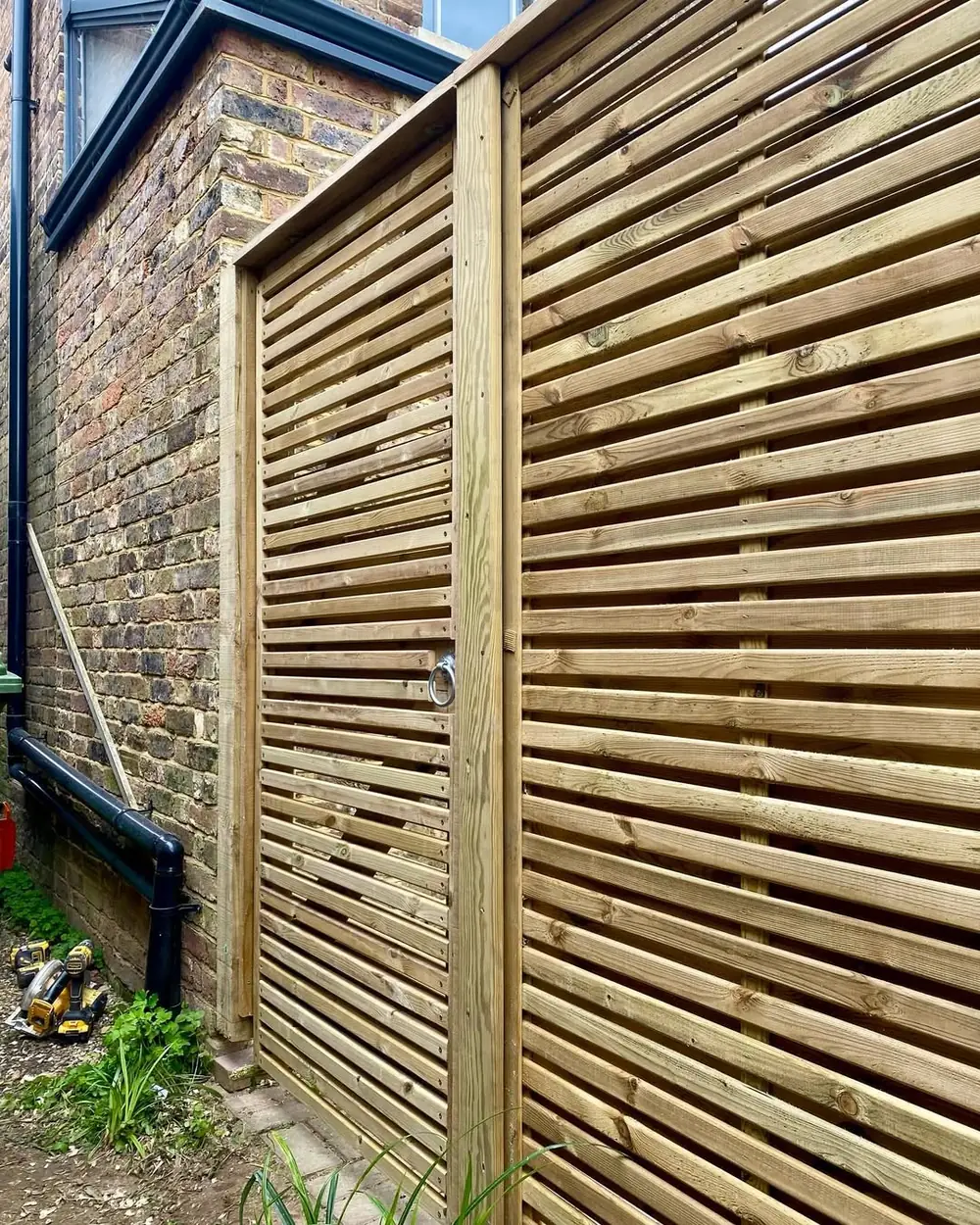 Venetian slatted panels forming a screen against a brick wall